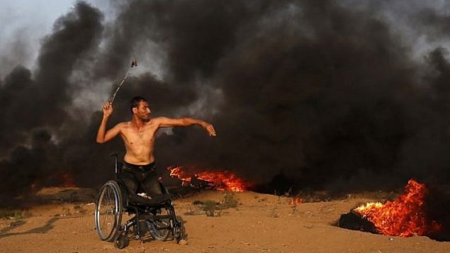 محتج فلسطيني على كرسي متحرك يلقي بالحجارة باتجاه القوات الإسرائيلية خلال اشتباكات على طول السياج الحدودي الإسرائيلي، شرق مدينة غزة في 28 سبتمبر 2018. (AFP PHOTO / Said KHATIB)
