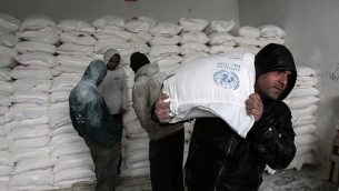 فلسطينيون يجمعون المساعدات الغذائية في مركز لتوزيع الغذاء تابع للأمم المتحدة في خان يونس، جنوب قطاع غزة، 28 يناير، 2018. (Said Khatib/AFP)