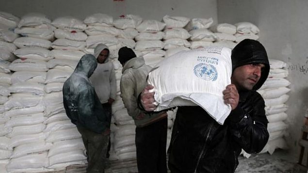 فلسطينيون يجمعون المساعدات الغذائية في مركز لتوزيع الغذاء تابع للأمم المتحدة في خان يونس، جنوب قطاع غزة، 28 يناير، 2018. (Said Khatib/AFP)