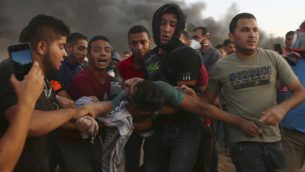 متظاهرون يخلون مراهقا اصيب بالقرب من الحدود بين قطاع غزة واسرائيل خلال مظاهرة، شرقي مدينة غزة، 14 سبتمبر 2018 (AP Photo/Adel Hana)