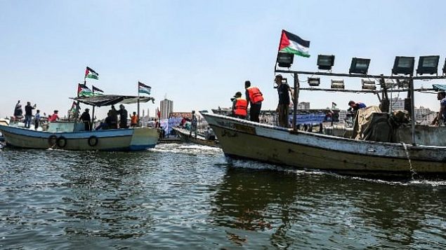 ناشطون يرافقون قارب على متنه فلسطينيين اصيبوا خلال الاشتباكات عند السياج الامني حول غزة، اثناء محاولته كسر الحصار البحري الذي تفرضه اسرائيل، 10 يوليو 2018 (Mahmud Hams/AFP)