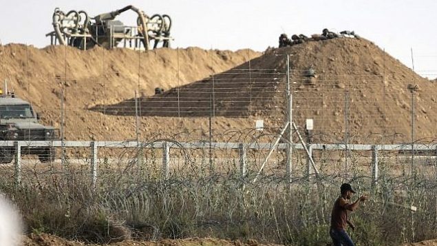 فلسطيني يستخدم مقلاع لرشق القوات الإسرائيلية في الطرف الاخر من الحدود بالحجارة خلال اشتباكات عند الحدود مع اسرائيل شرقي مدينة غزة، 13 يوليو 2018 (AFP PHOTO / MAHMUD HAMS)