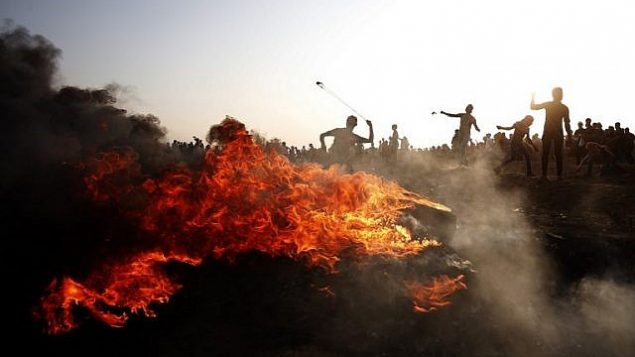 فلسطينيون يلقون الحجارة باتجاه القوات الإسرائيلية خلال مواجهات على الحدود بين إسرائيل وقطاع غزة، شرقي مدينة غزة، 28 سبتمبر، 2018. (AFP Photo/Said Khatib)