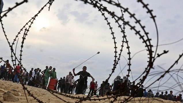 متظاهر فلسطيني يلقي حجرا باتجاه القوات الإسرائيلية خلال مواجهات على شاطئ بالقرب من الحدود البحرية بين قطاع غزة واسرائيل، 1 اكتوبر 2018 (AFP Photo/Said Khatib) متظاهر فلسطيني يلقي حجرا باتجاه القوات الإسرائيلية خلال مواجهات على شاطئ بالقرب من الحدود البحرية بين قطاع غزة واسرائيل، 1 اكتوبر 2018 (AFP Photo/Said Khatib)