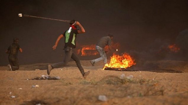 فلسطيني يرمي حجرا تجاه القوات الإسرائيلية خلال اشتباكات شرق مدينة غزة على طول الحدود بين قطاع غزة وإسرائيل، في 5 أكتوبر 2018. (AFP Photo / Said Khatib)