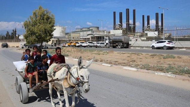 فلسطييون يركبون عربة مربوطة بحمار بالقرب من محطة الكهبراء في النصيرات، في وسط قطاع غزة، 9 أكتوبر، 2018. (AFP/Said Khatib)