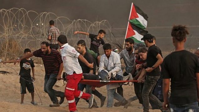 مسعفون فلسطينيون يحملون متظاهر مصاب خلال تظاهرة بالقرب من الحدود مع إسرائيل، شرق مدينة غزة، في 19 أكتوبر 2018. (MAHMUD HAMS / AFP)