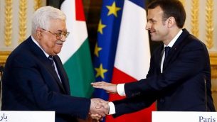 الرئيس الفرنسي إيمانويل ماكرون يصافح رئيس السلطة الفلسطينية محمود عباس في نهاية مؤتمر صحفي مشترك بعد لقاء جمعهما في قصر الإليزيه في باريس، 22 ديسمبر، 2017.  (AFP/Pool/Francois Mori)