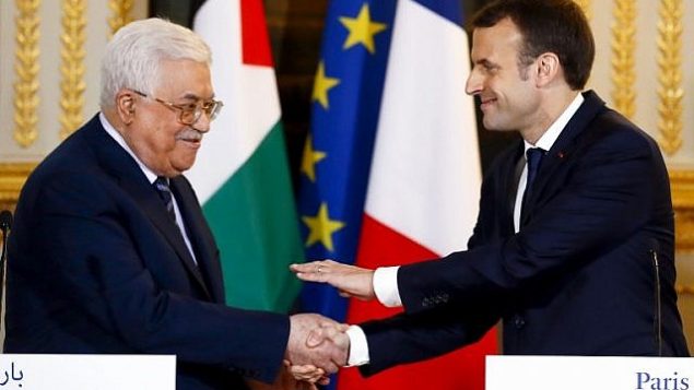 الرئيس الفرنسي إيمانويل ماكرون يصافح رئيس السلطة الفلسطينية محمود عباس في نهاية مؤتمر صحفي مشترك بعد لقاء جمعهما في قصر الإليزيه في باريس، 22 ديسمبر، 2017.  (AFP/Pool/Francois Mori)