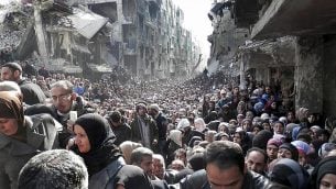 ملف - في 31 كانون الثاني / يناير 2014، تظهر صورة الملف الصادرة عن الأونروا، سكان مخيم اليرموك الفلسطيني المحاصر، يصطفون للحصول على الإمدادات الغذائية، في دمشق، سوريا (UNRWA via AP, File)