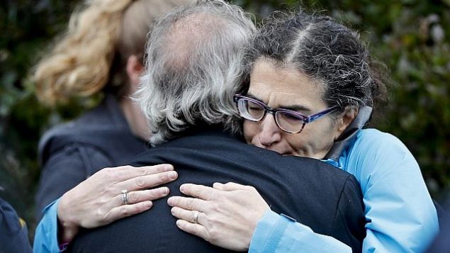 الناس يتعانقون على طول الشارع في حي تلة سكويرل في بيتسبرغ حيث أطلق مهاجم النار خلال الصلاة في كنيس شجرة الحياة يوم السبت 27 أكتوبر، 2018. (AP/Keith Srakocic)