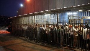 عمال فلسطينيون يقفون في انتظار اجتياز حاجز للعمل في إسرائيل عند الجدار الأمني في مدينة بيت لحم في الضفة الغربية، 23 أغسطس، 2010.  (Najeh Hashlamoun/Flash 90)