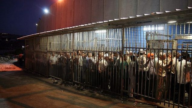 عمال فلسطينيون يقفون في انتظار اجتياز حاجز للعمل في إسرائيل عند الجدار الأمني في مدينة بيت لحم في الضفة الغربية، 23 أغسطس، 2010.  (Najeh Hashlamoun/Flash 90)