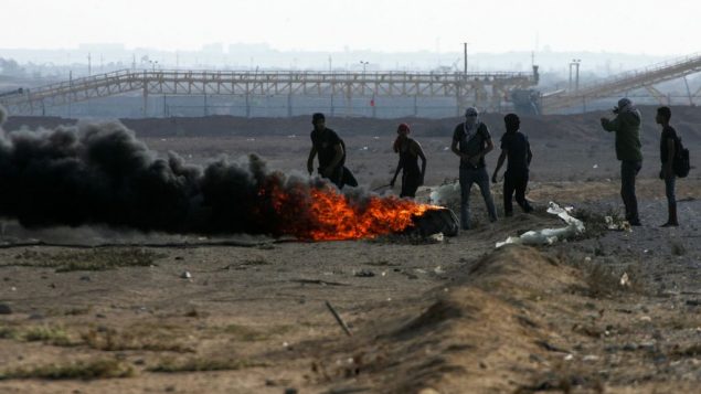 متظاهرون فلسطينيون يحرقون إطارات خلال مظاهرات ’مسيرة العودة’، عند الحدود بين اسرائيل وقطاع غزة، في رفح، 12 اكتوبر 2018 (Abed Rahim Khatib/Flash90)