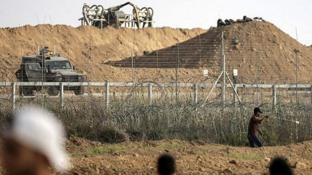 فلسطيني يستخدم المقلاع لإلقاء حجارة باتجاه القوات الإسرائيلي على الجانب الآخر من السياج الحدودي خلال مواجهات حدودية مع إسرائيل في شرق مدينة غزة، 13 يوليو، 2018. (AFP PHOTO / MAHMUD HAMS)