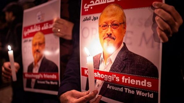 يحمل الناس ملصقات تصور الصحفي السعودي جمال خاشقجي والشموع خلال تجمع خارج القنصلية السعودية في اسطنبول، في 25 أكتوبر 2018. (Yasin Akgul/AFP)
