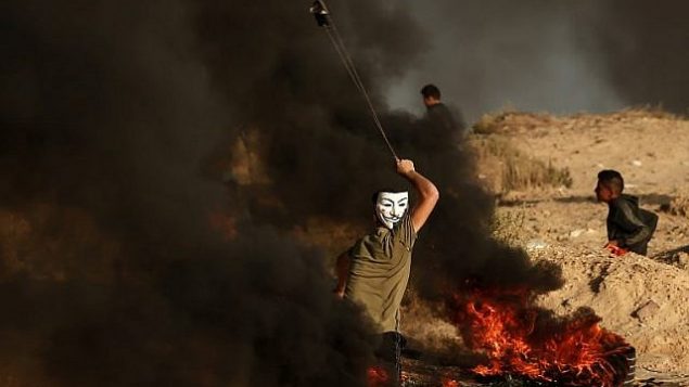 فلسطييني يستخدم المقلاع لإلقاء حجارة خلال مظاهرة على الشاطئ بالقرب من الحدود البحرية مع إسرائيل، في بيت لاخيا في جنوب قطاع غزة، 29 أكتوبر، 2018. (MAHMUD HAMS / AFP)