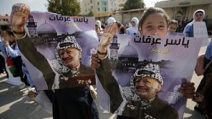 فتاة تحمل صورة الزعيم الراحل ياسر عرفات بينما يحتفل الفلسطينيون بالذكرى الرابعة عشرة لوفاته في مدينة رام الله بالضفة الغربية، في 11 نوفمبر / تشرين الثاني 2018. (ABBAS MOMANI/AFP)
