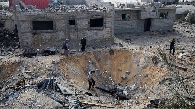 فلسطينيون يفحصون حفرة ناتجة عن غارة اسرائيلية خلال القتال مع حركات فلسطينية، في رفح، جنوب قطاع غزة، 14 نوفمبر 2018 (Said Khatib/AFP)