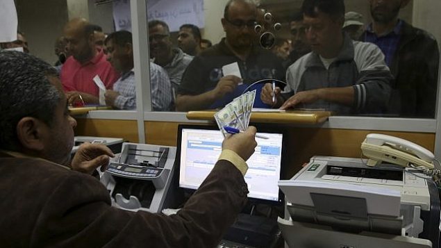 موظف حكومي فلسطيني لدى حماس يوقع من اجل الحصول على 60% من اجره المتأخر بينما ينتظر اخرون، في مكتب البريد المركزي في غزة، 9 نوفمبر 2018 (AP/Adel Hana)