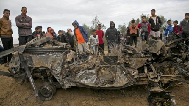 فلسطينيون يقفون بالقرب من مركبة، ورد أنه تم تدميرها في أعقاب غارة جوية إسرائيلية في خان يونس في جنوب قطاع غزة، 12 نوفمبر، 2018. (Photo by SAID KHATIB / AFP)