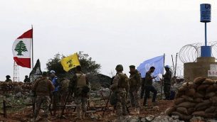 صورة التقطت من قرية ميس الجبل اللبنانية، تظهر جنود اسرائيليون يراقبون بينما جنود قوات حفظ السلام الأممية يتحدثون مع جنود لبنانيين امام علم حزب الله، 16 ديسمبر 2018 (Mahmoud ZAYYAT / AFP)