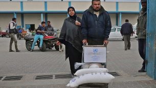 رجل فلسطيني ينقل أكياسا من الطحين خارج مركز توزيع المساعدات الذي تديره وكالة الأمم المتحدة لإغاثة وتشغيل اللاجئين الفلسطينيين في رفح في جنوب قطاع غزة، في 20 كانون الأول / ديسمبر 2018. (Said Khatib/AFP)