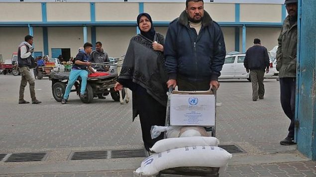 رجل فلسطيني ينقل أكياسا من الطحين خارج مركز توزيع المساعدات الذي تديره وكالة الأمم المتحدة لإغاثة وتشغيل اللاجئين الفلسطينيين في رفح في جنوب قطاع غزة، في 20 كانون الأول / ديسمبر 2018. (Said Khatib/AFP)