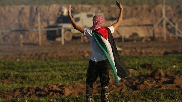 متظاهر يضع على كتفيه بالعلم الفلسطيني خلال مواجهات مع القوات الإسرائيلية بعد مظاهرة على الحدود مع إسرائيل في شرق مدينة غزة، 18 يناير، 2019. (Said KHATIB / AFP) متظاهر يضع على كتفيه بالعلم الفلسطيني خلال مواجهات مع القوات الإسرائيلية بعد مظاهرة على الحدود مع إسرائيل في شرق مدينة غزة، 18 يناير، 2019. (Said KHATIB / AFP)