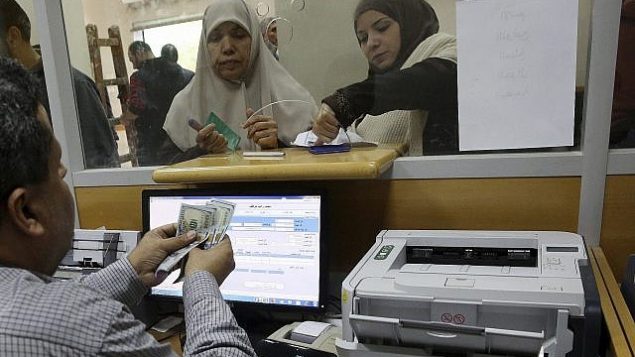 موظفة حكومية معينة من قبل حماس في غزة توقع على وثيقة للحصول على 50% من راتبها المتأخر من أموال تبرعت بها قطر، مع انتظار الآخرين في الطابور، في مكتب البريد الرئيسي في غزة، 7 ديسمبر، 2018.  (AP Photo/Adel Hana)