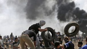 متظاهرون فلسطينيون يحرقون إطارات بالقرب من حدود غزة-إسرائيل، شرق مدينة غزة، خلال مظاهرات احتجاجا على افتتاح السفارة الأمريكية في القدس، 14 مايو، 2018.  (AFP Photo/Mahmud Hams)
