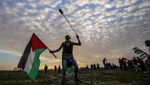 متظاهر فلسطيني يحمل العلم الوطني ومقلاع خلال مظاهرات بالقرب من السياج عند الحدود مع اسرائيل، شرقي مدينة غزة، 1 فبراير 2019 (Said Khatib/AFP)