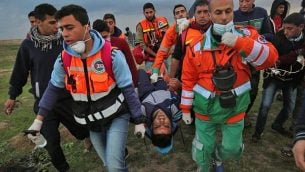 مسعفون فلسطينيوم ينقلون شابا مصابا خلال مواجهات في اعقاب مظاهرة عند الحدود مع إسرائيل شرق مدينة غزة، 1 مارس، 2019.  (SAID KHATIB / AFP)
