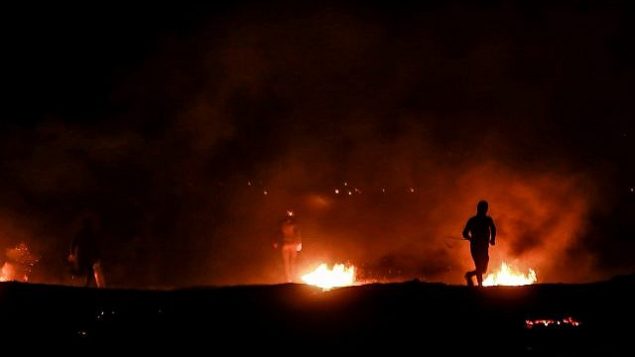 متظاهرون فلسطينيون يحرقون إطارات خلال مظاهرة ليلية بالقرب من الحدود مع إسرائيل، شرق مدينة رفح في جنوب قطاع غزة، 19 مارس، 2019. (Abed Rahim Khatib/ Flash90) متظاهرون فلسطينيون يحرقون إطارات خلال مظاهرة ليلية بالقرب من الحدود مع إسرائيل، شرق مدينة رفح في جنوب قطاع غزة، 19 مارس، 2019. (Abed Rahim Khatib/ Flash90)