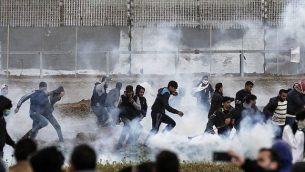 المتظاهرون الفلسطينيون يركضون للاحتماء من عبوات الغاز المسيل للدموع التي أطلقتها القوات الإسرائيلية خلال الاشتباكات وسط مظاهرة حاشدة احتفالا بالذكرى السنوية الأولى لاحتجاجات مسيرة العودة، بالقرب من الحدود مع إسرائيل شرق مدينة غزة في 30 مارس 2019. (Mahmud Hams/AFP)