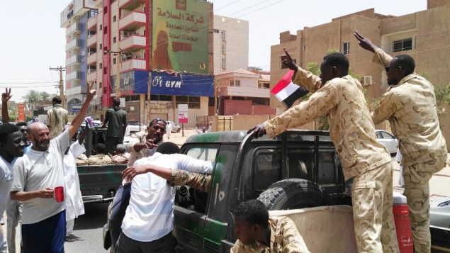 سودانيون وعناصر من قوى الأمن يشيرون بعلامة النصر في 11 أبريل، في العاصمة الخرطوم.  (Photo by - / AFP)