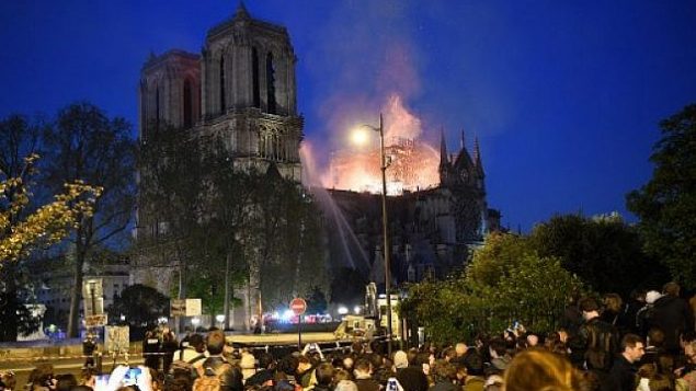 اشخاص يشاهدون الدخان والنيران تتصاعد من كاتدرائية نوتردام في باريس، 15 ابريل 2019 (ERIC FEFERBERG / AFP)