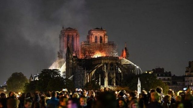 اشخاص يشاهدون الدخان والنيران تتصاعد من كاتدرائية نوتردام في باريس، 15 ابريل 2019 (ERIC FEFERBERG / AFP)