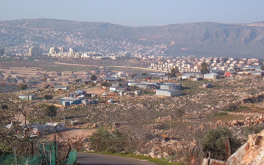 صورة لقرية عرب النعيم البدوية في المقدمة، مع مدينة كرمئيل في الخلفية، 25 فبراير، 2006. (Public Domain/Wikipedia) صورة لقرية عرب النعيم البدوية في المقدمة، مع مدينة كرمئيل في الخلفية، 25 فبراير، 2006. (Public Domain/Wikipedia)
