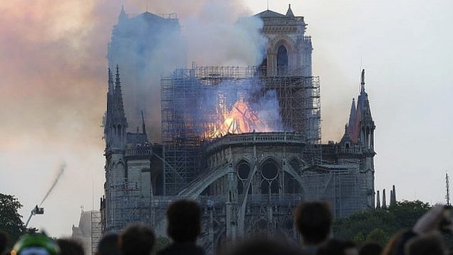 اشخاص يشاهدون الدخان والنيران تتصاعد من كاتدرائية نوتردام في باريس، 15 ابريل 2019 (AP Photo/Thibault Camus)
