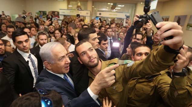 رئيس الوزراء بنيامين نتنياهو يلتقط صورة مع جندي خلال حدث للجنود الوحيدين في تل ابيب، 24 يناير 2019 (Marc Israel Sellem/Pool/Flash90)