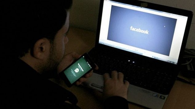 صورة توضيحية لرجل يجلس أمام شاشة كمبيوتر يظهر عليها شعار ’فيسبوك’، 26 فبراير، 2014.(Abed Rahim Khatib/Flash90)