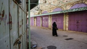 سيدة فلسطينية تمشي بين متاجر مغلقة خلال اضراب احتجاجا على قانون الضمان الاجتماعي الذي اقترحته السلطة الفلسطينية، في مدينة الخليل في الضفة الغربية، 15 يناير 2019 (HAZEM BADER / AFP)