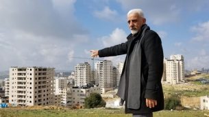 الناشط منير زغاير، الذي يترأس لجنة تقدم بانتظام شكاوى لبلدية القدس حول وضع الخدمات في كفر عقب، يشير إلى عدد من المباني في الحي التي تم بناؤها بشكل يتعارض مع المعايير، 20 فبراير، 2019. (Adam Rasgon/Times of Israel)
