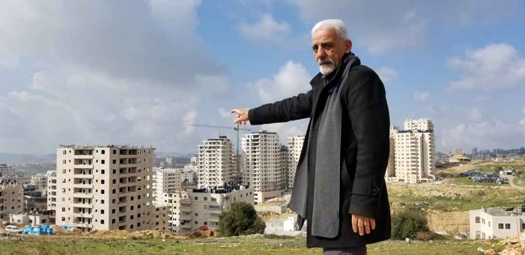 الناشط منير زغاير، الذي يترأس لجنة تقدم بانتظام شكاوى لبلدية القدس حول وضع الخدمات في كفر عقب، يشير إلى عدد من المباني في الحي التي تم بناؤها بشكل يتعارض مع المعايير، 20 فبراير، 2019. (Adam Rasgon/Times of Israel) الناشط منير زغاير، الذي يترأس لجنة تقدم بانتظام شكاوى لبلدية القدس حول وضع الخدمات في كفر عقب، يشير إلى عدد من المباني في الحي التي تم بناؤها بشكل يتعارض مع المعايير، 20 فبراير، 2019. (Adam Rasgon/Times of Israel)