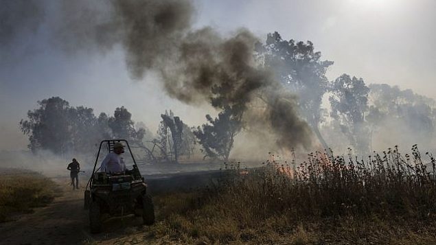 رجال إطفاء إسرائيليون يكافحون النيران التي اشتعلت جراء إطلاق بالونات حارقة من قطاع غزة، بالقرب من السياج الحدودي بين إسرائيل وغزة، الأربعاء، 15 مايو، 2019. (AP/Tsafrir Abayov) رجال إطفاء إسرائيليون يكافحون النيران التي اشتعلت جراء إطلاق بالونات حارقة من قطاع غزة، بالقرب من السياج الحدودي بين إسرائيل وغزة، الأربعاء، 15 مايو، 2019. (AP/Tsafrir Abayov)