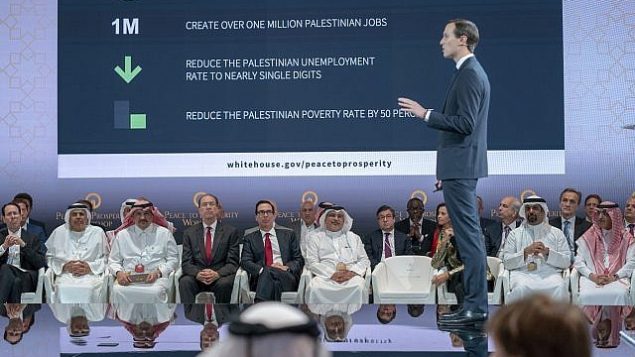 وزير الخزانة الأمريكي ستيفين منوشين، الخامس من اليسار، وولي العهد البحريني سلمان بن حمد آل خليفة، السادس من اليسار، يستمعان للمستشار الكبير للبيت الأبيض جاريد كوشنر، الواقف في الصورة، خلال الجلسة الافتتاحية لورشة "السلام من أجل الازدهار" في المنامة، البحرين، 25 يونيو، 2019.  (Bahrain News Agency via AP)