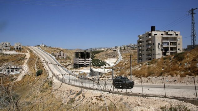 صورة التقطت من قرية بيت ساحور الفلسطينية في الضفة الغربية، تظهر سيارة شرطة اسرائيلية تمر بجانب منازل تم اصدار اوامر بهدمها، في حي صور باهر في القدس الشرقية، 11 يوليو 2019 (HAZEM BADER/AFP)