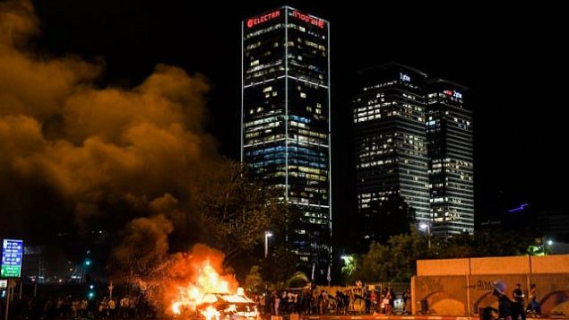 مركبة محترقة خلال احتجاجات في أعقاب مقتل الشاب من أصول إثيوبية سولومون تيكاه (19 عاما) قبل بضعة أيام في بلدة كريات يام برصاص شرطي خارج الخدمة، في مدينة تل أبيب، 2 يوليو، 2019. ( Flash90)