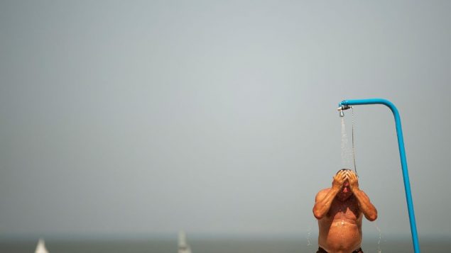 رجل يبرد جسده في شاطء خلال يوم صيف حار في بلجيكا، 25 يوليو 2019 (AP Photo/Francisco Seco)